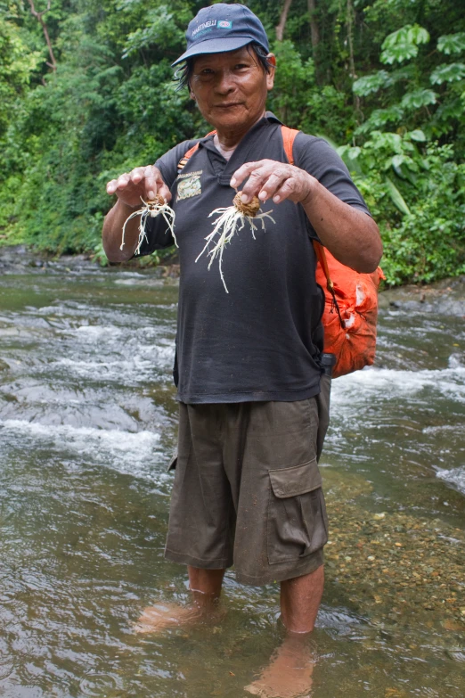 a man standing on top of a river holding plants