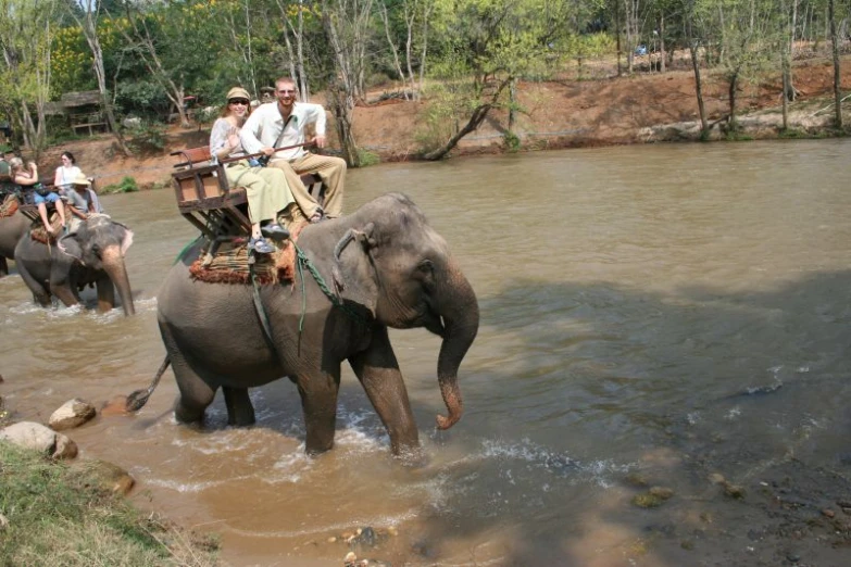 a group of people riding elephants through a lake