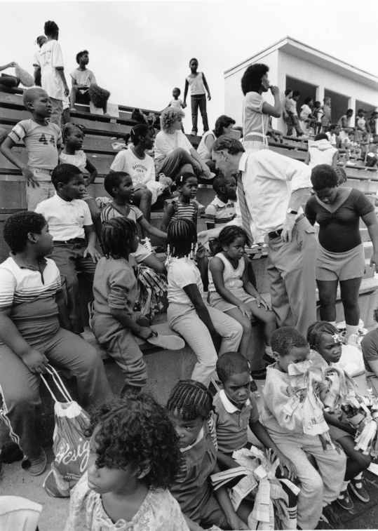 children on bleachers sitting around and looking at someone