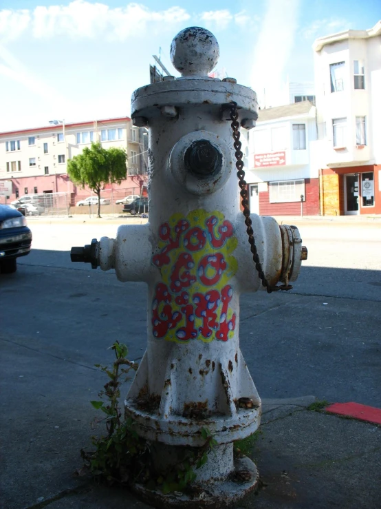 a white fire hydrant covered with graffiti next to a road