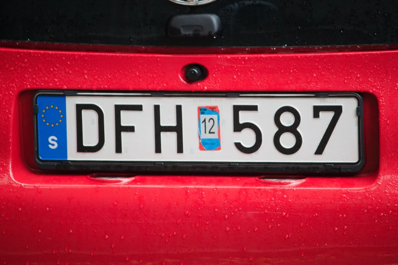 the license plate of an automobile in front of a red car