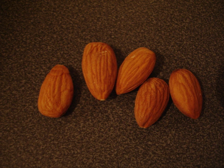 five almonds sitting in a pile on top of a brown surface