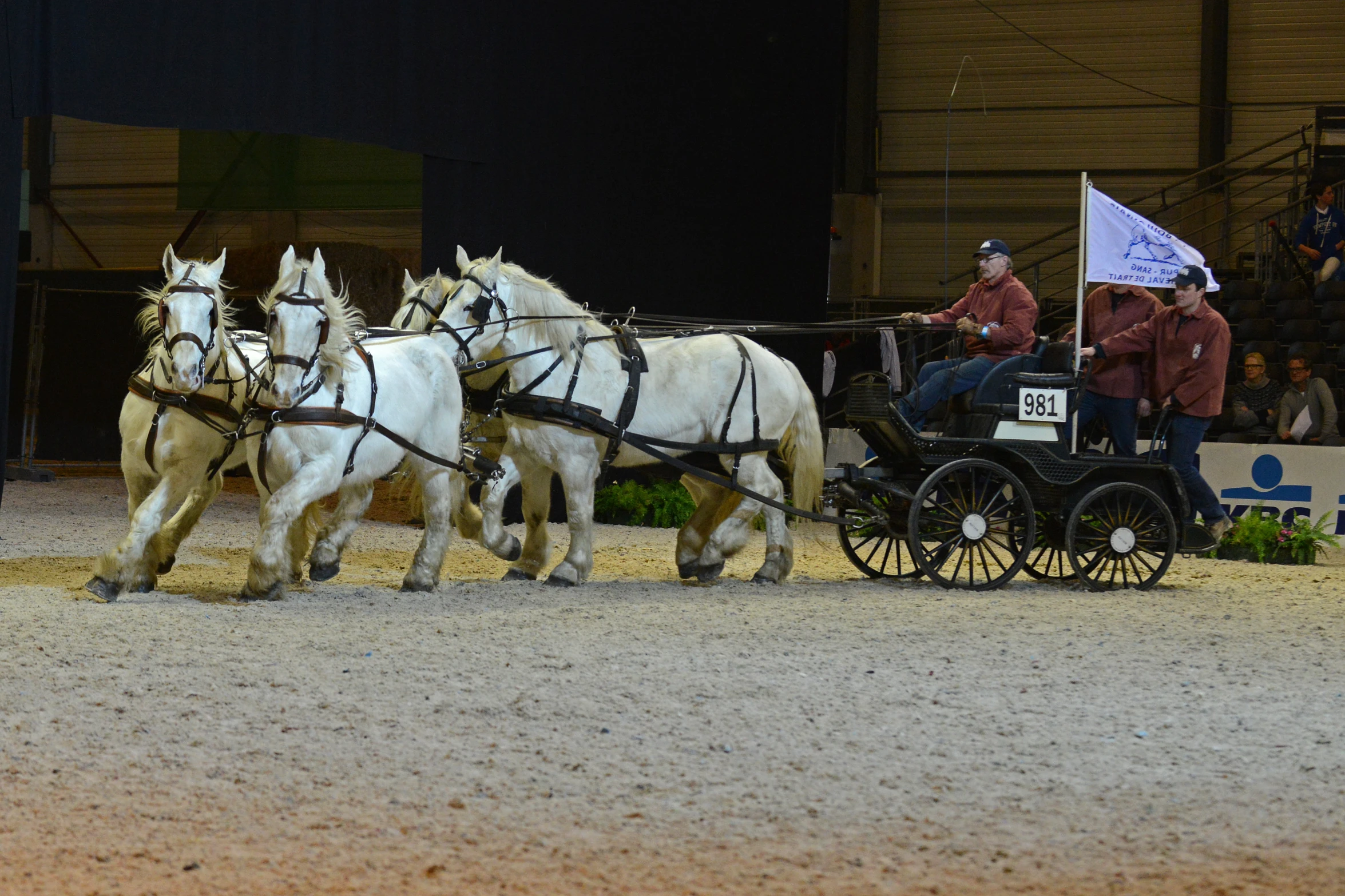 two horse drawn carriages in an arena with people