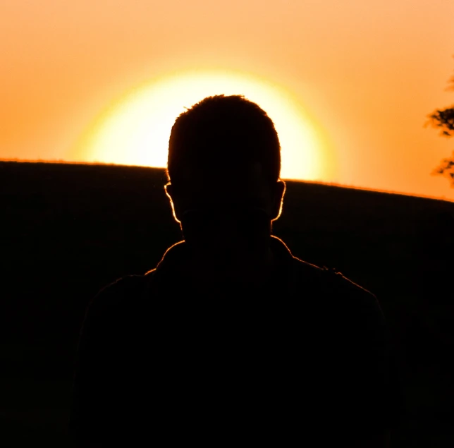 a silhouette of a man looking at the sun