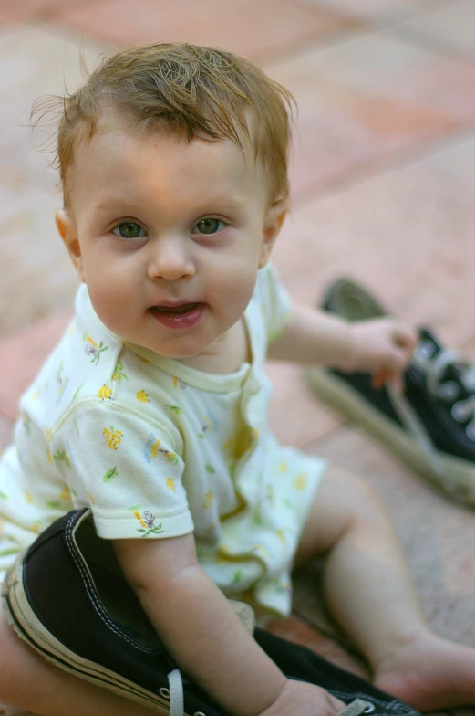 a baby is sitting on the ground next to his shoes