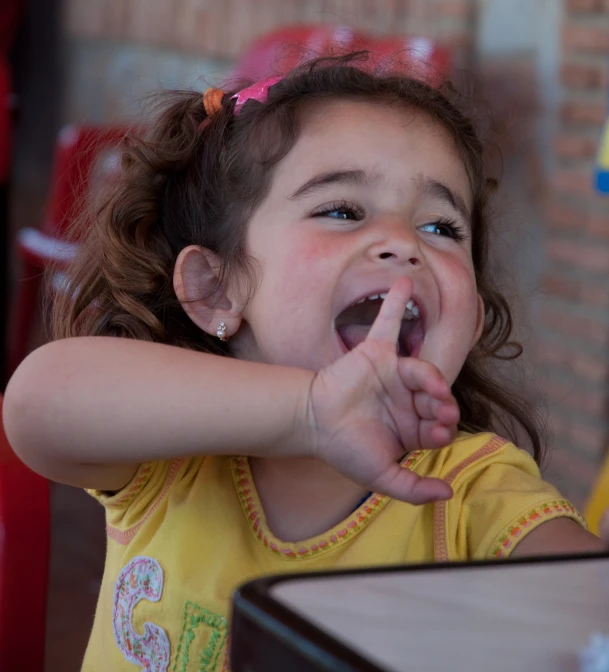 little girl in yellow shirt covering her mouth