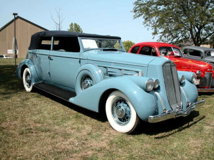 the old fashioned cars are parked in the grass