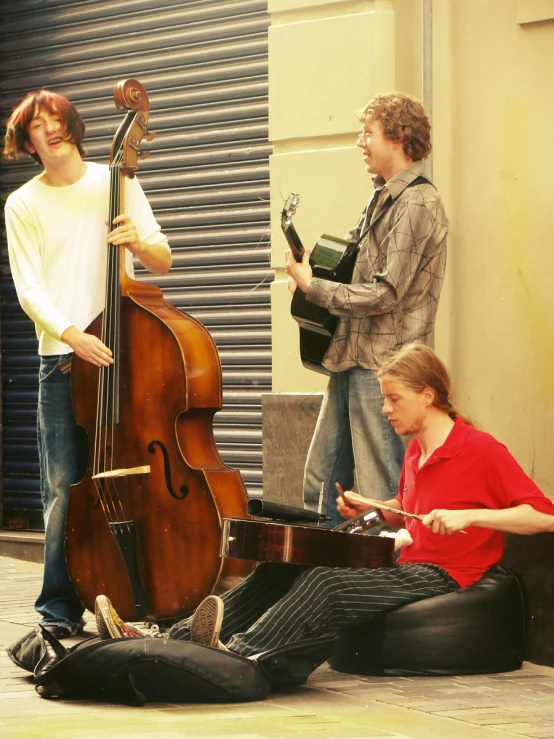 three guys and one woman playing guitar in a city