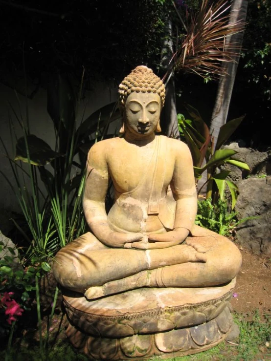 a stone statue of a buddha meditating outside