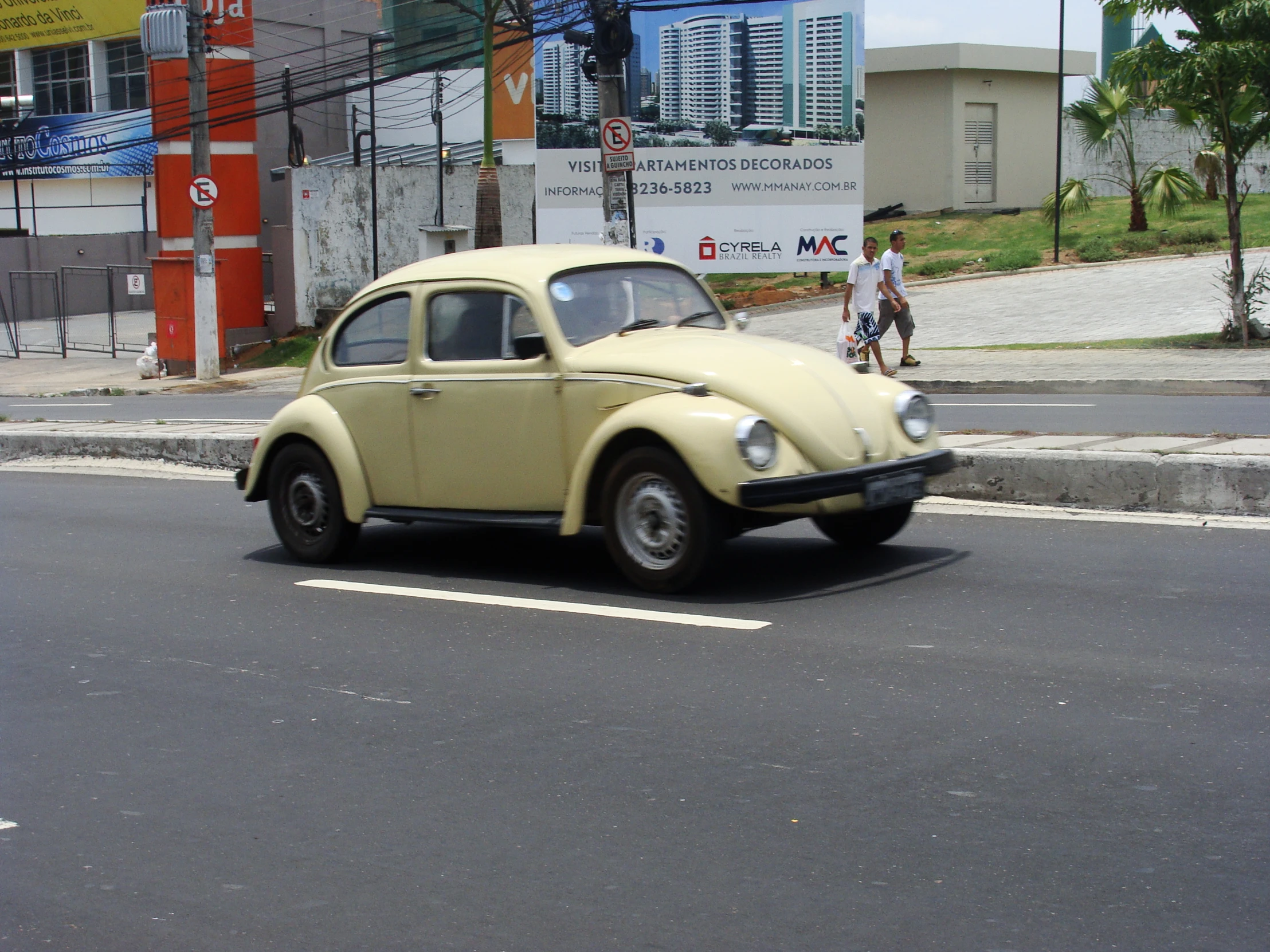 the old vw bug is traveling down the street