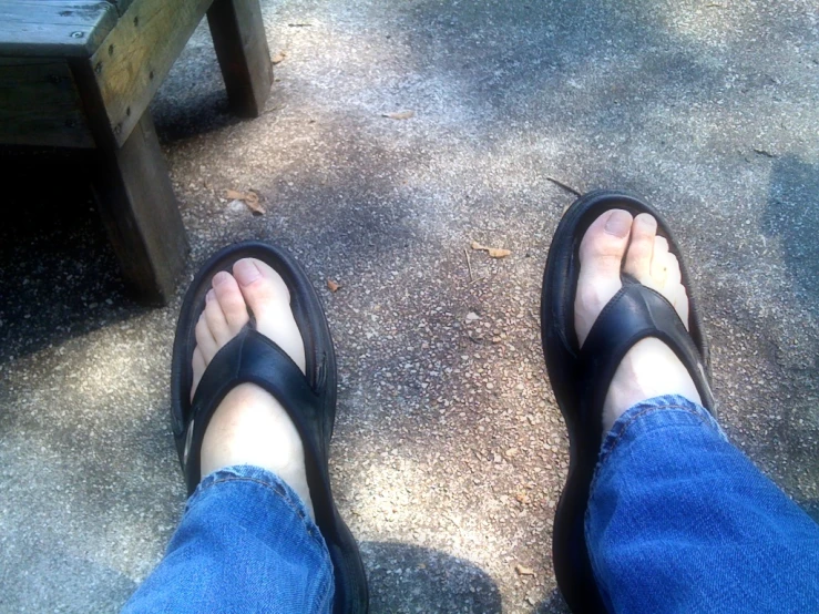 a person wearing sandals stands in front of a bench