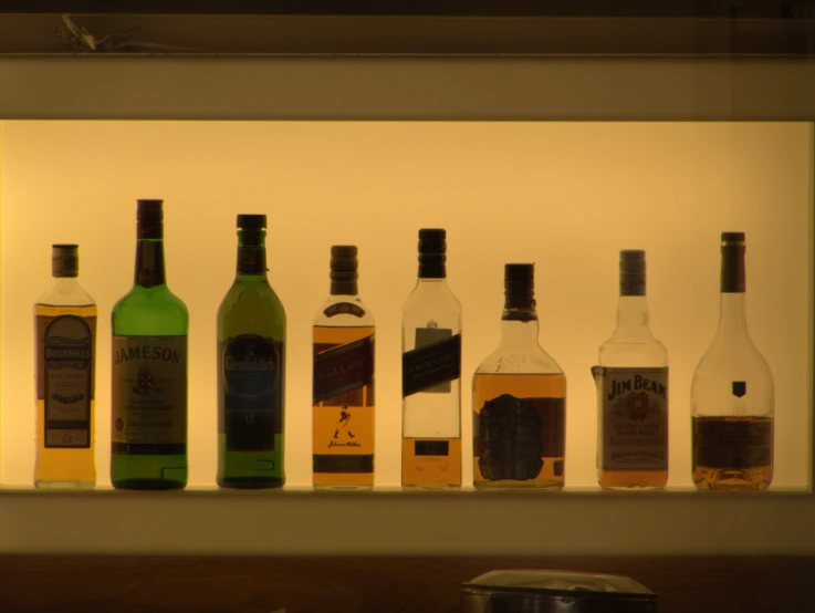 seven bottles of alcohol displayed on white shelf