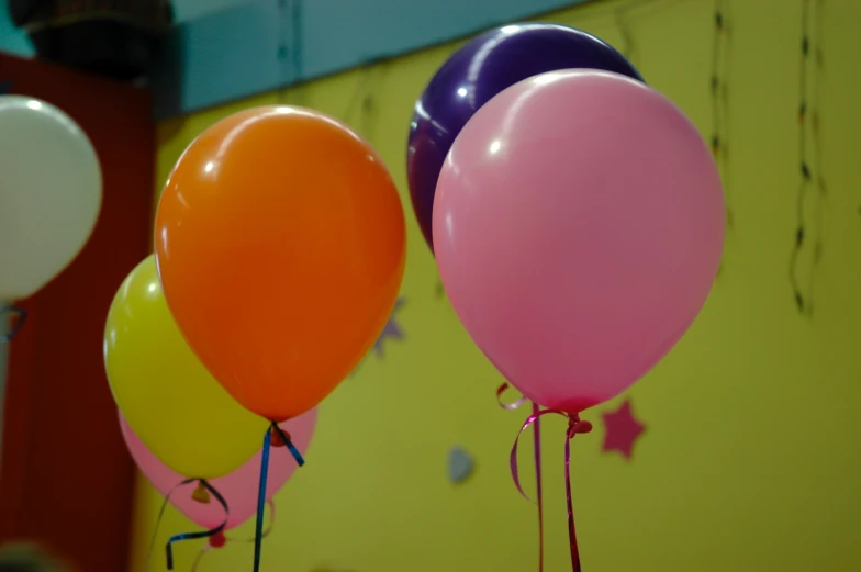 some balloons are in multiple colors by a wall