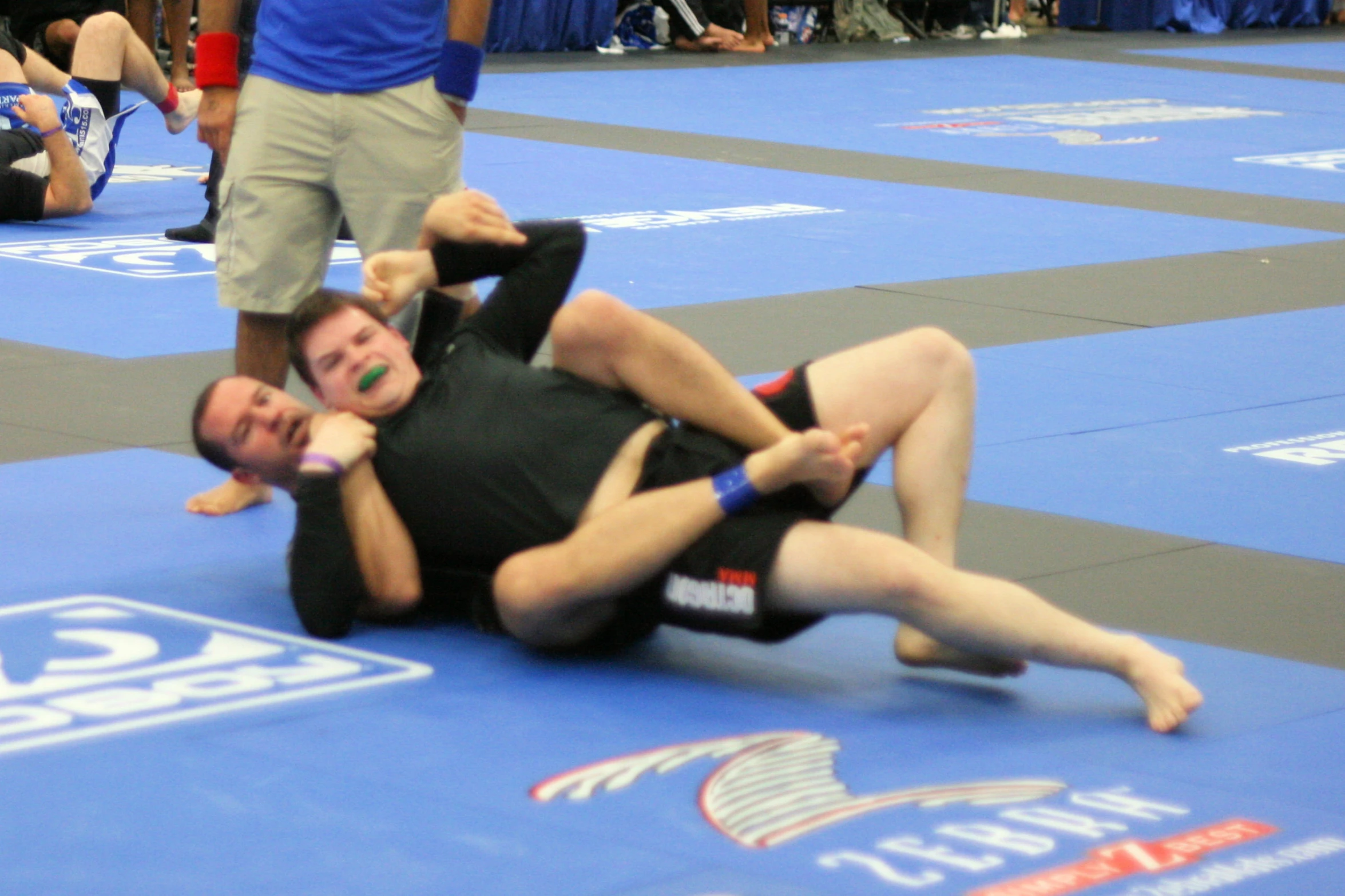 a man on a blue floor doing a trick with his leg