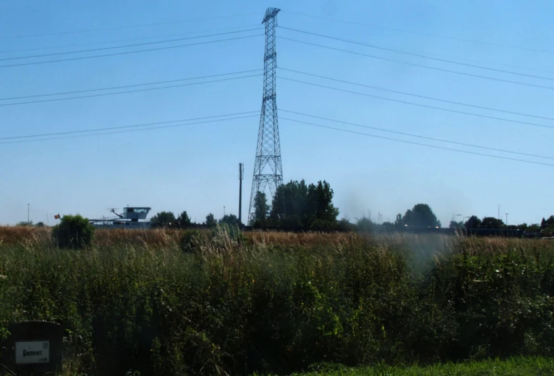 a big field with telephone towers and a train track