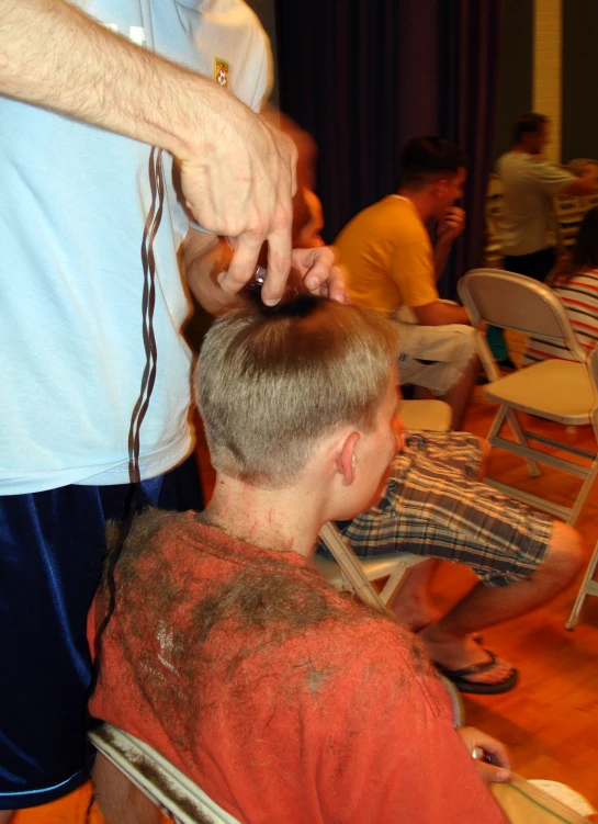 a boy getting his hair cut while two other people watch