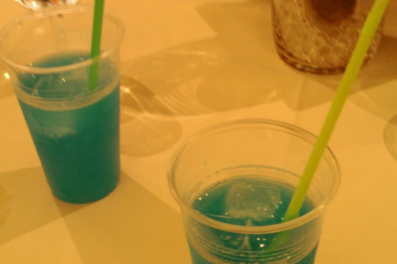 two glass cups with green drinks and blue liquid in them