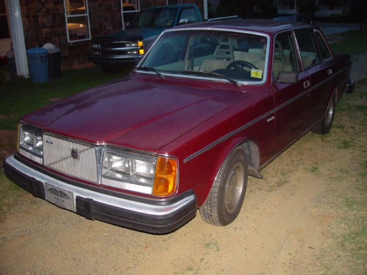 a maroon car is parked on the side of a road