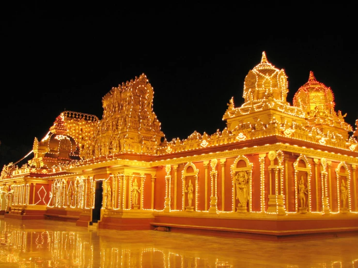 illuminated temple stands near a small pool in an urban area