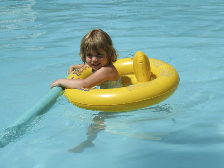 a little girl that is sitting in the water with a raft