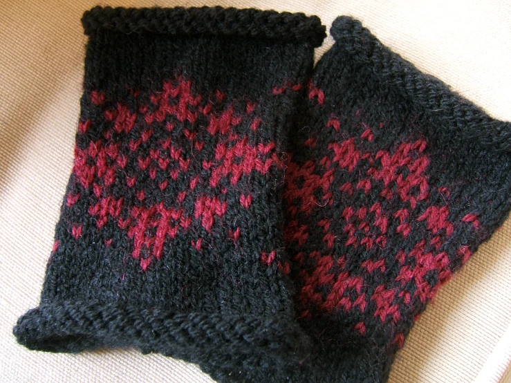 two gray and red mitts sitting on a blanket