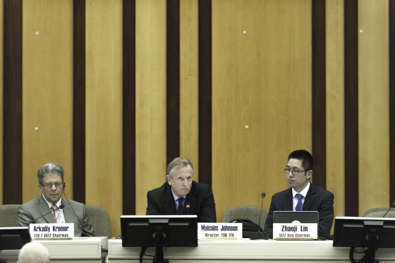 three men in suits are sitting at a table