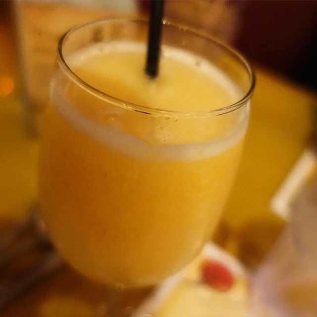 a glass of orange juice sitting on top of a wooden table