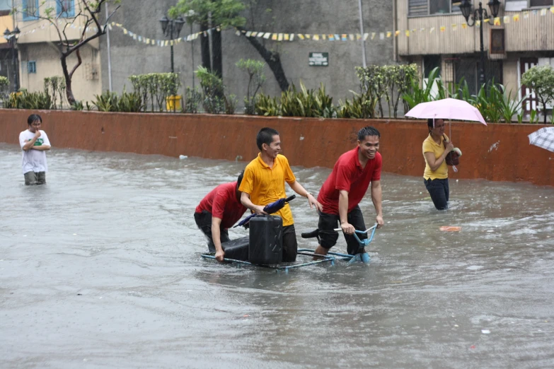 men use a wheelbarrow in a flooded city street