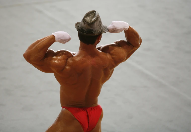 a man in red trunks is looking at his muscles