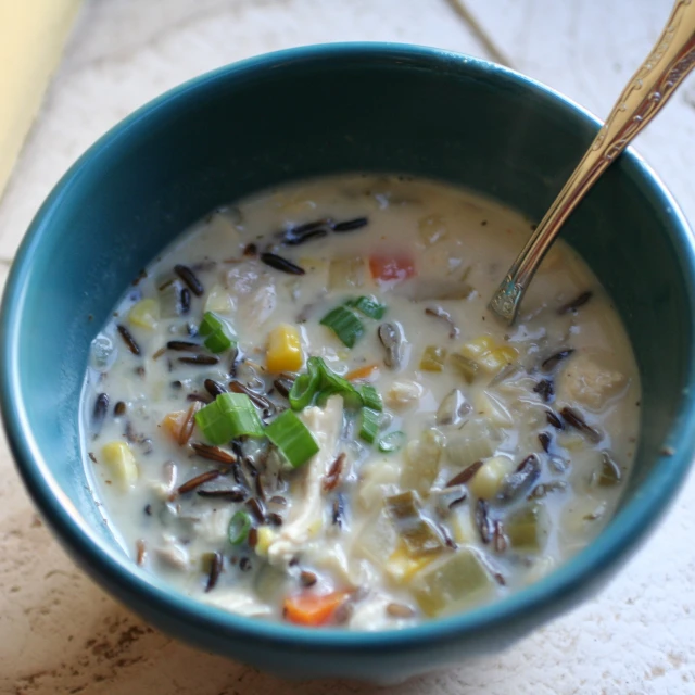 the bowl has soup with rice, carrots and other vegetables