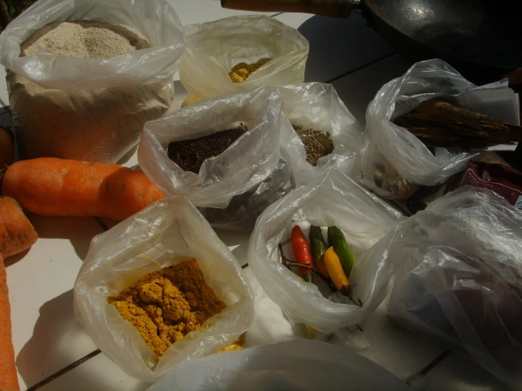 a group of bags of food including carrots, a peael, and spices