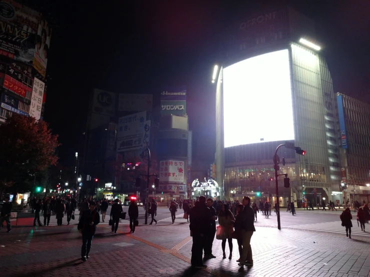 a crowd of people walking down a street at night