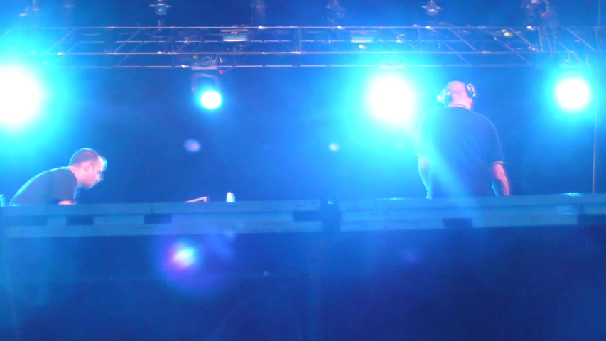 two men standing on stage with blue lights behind them