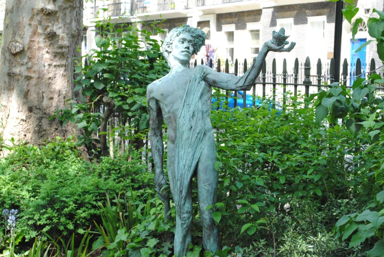 a statue in the bushes by a metal fence