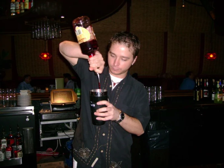 a man holding a small bottle and a glass in his hand