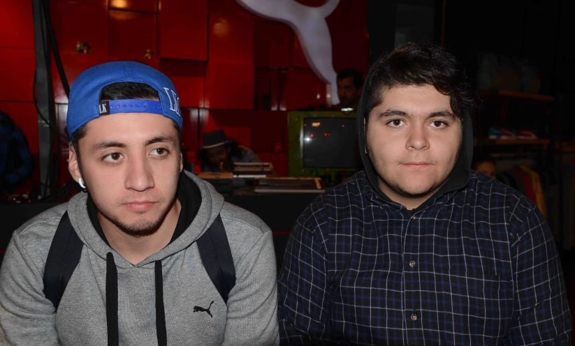 two males sitting with a tv in the background