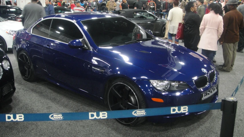 blue car being inspected at show with blue ribbon