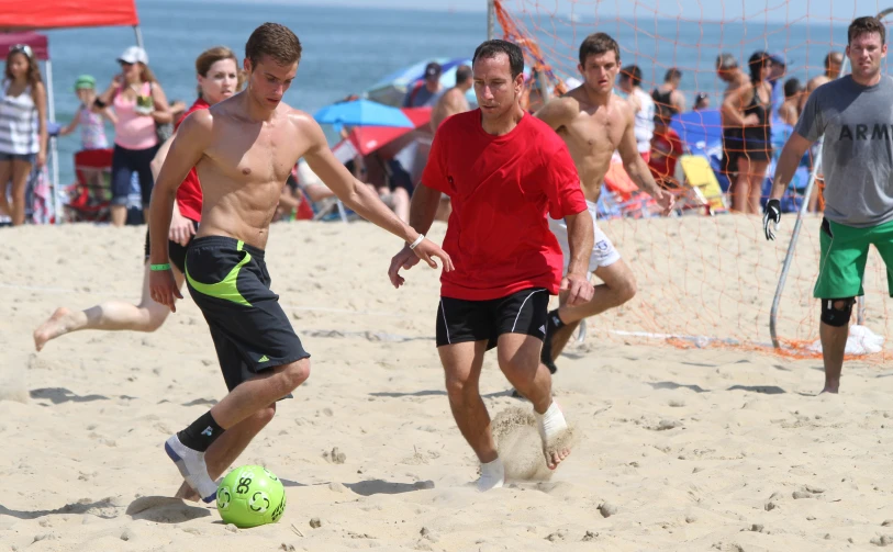 two men kicking around a ball on a beach
