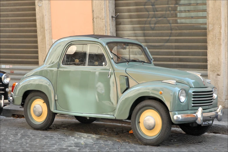 an old green car on the side of the street