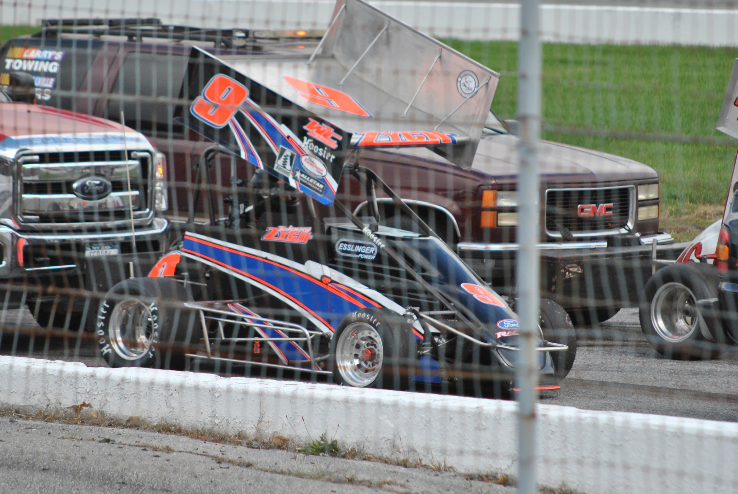 three racing cars behind the fence during a race