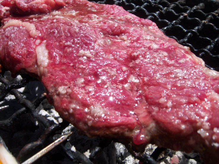 a large steak is cooking on an outdoor grill