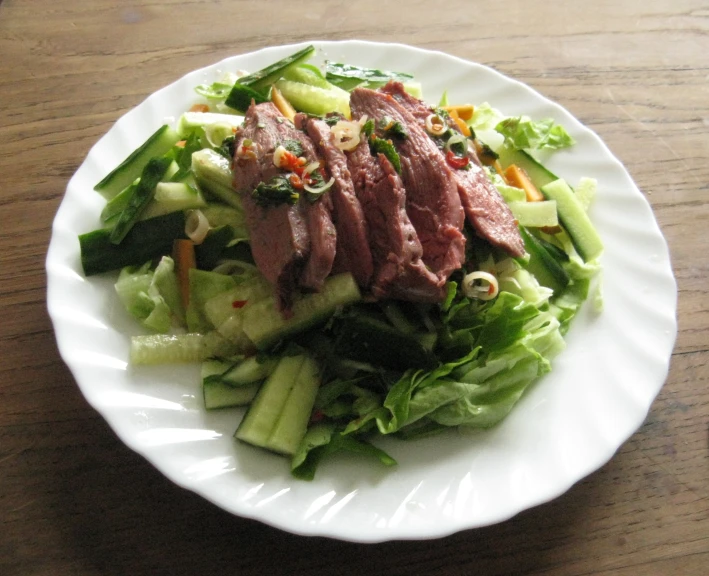 a white plate topped with sliced up meat and veggies
