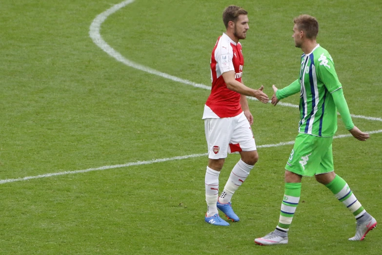 two soccer players are shaking hands on a field