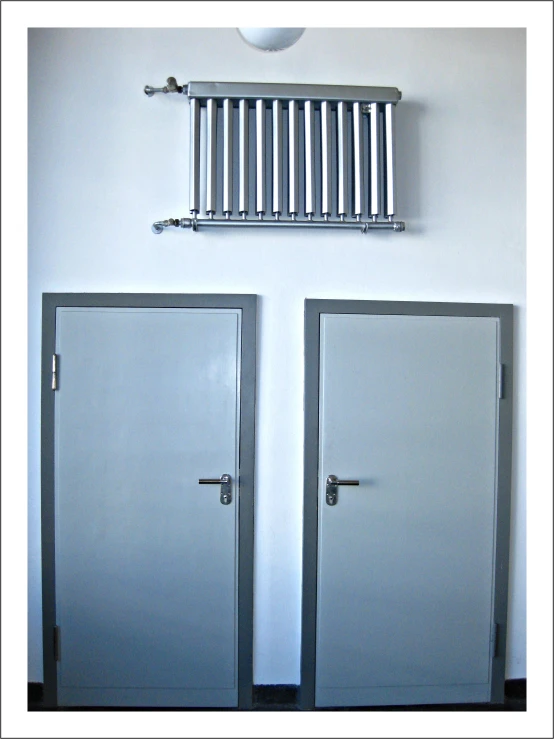 two doors in the corner of a room with bars on top of them