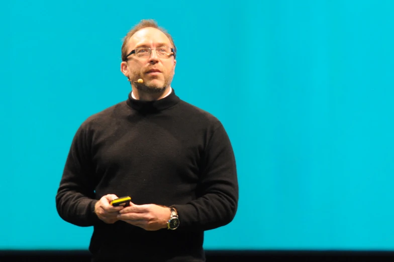 a man with glasses holding a cell phone