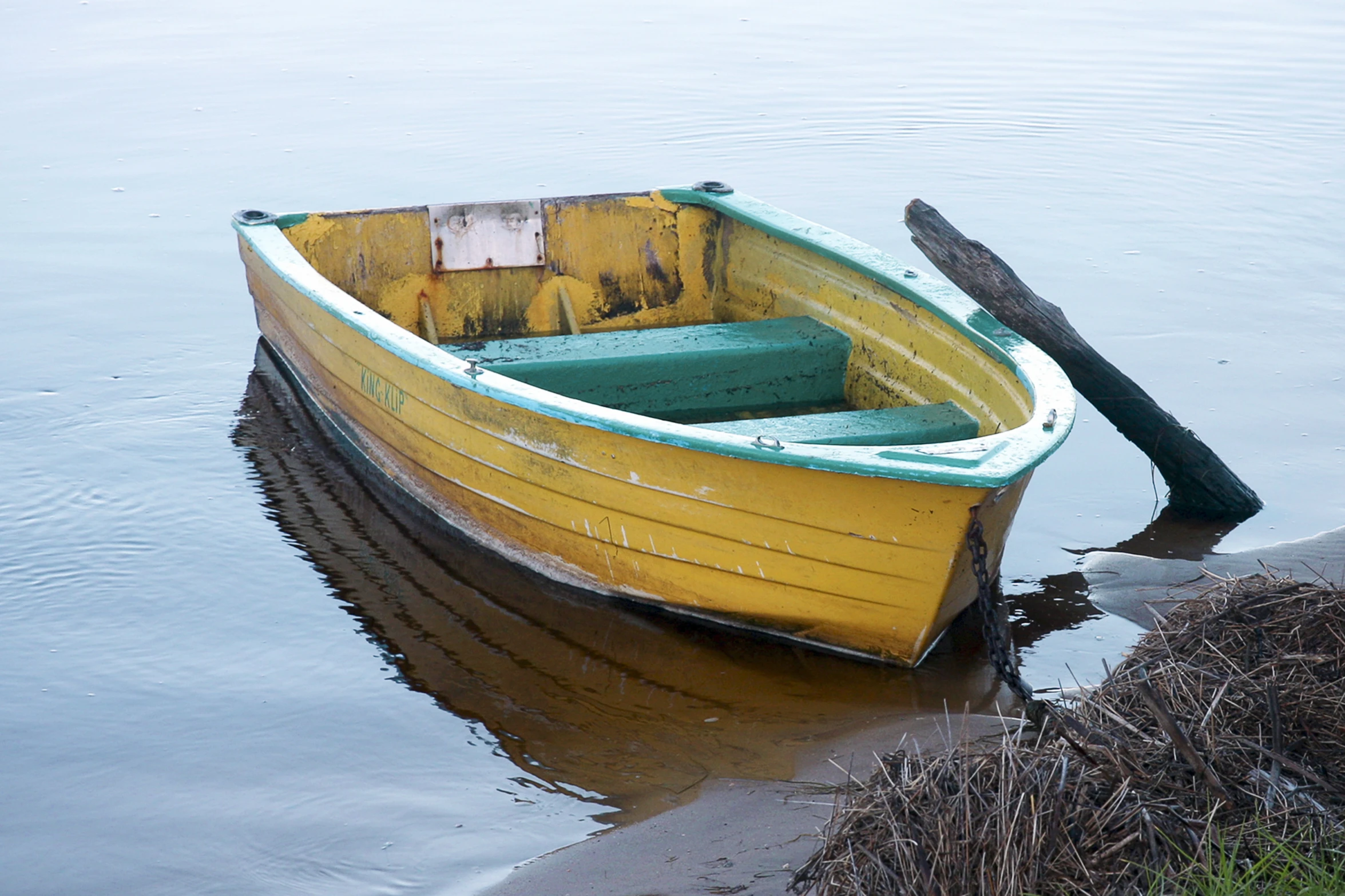 an old yellow and green row boat sitting in water