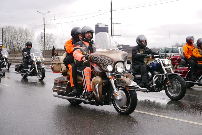 a group of people in orange jackets riding motorcycles