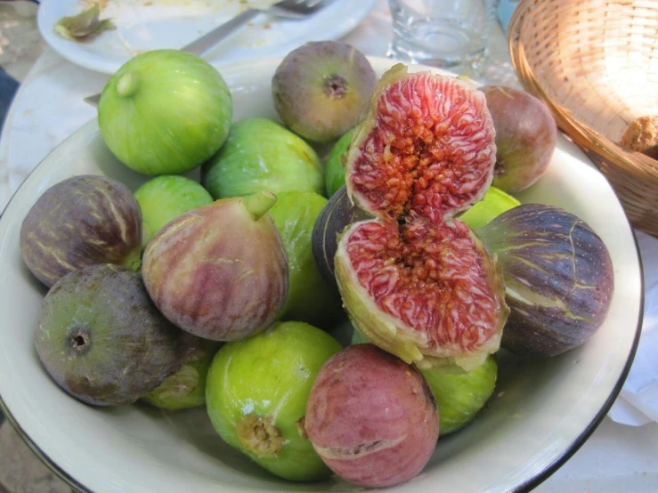 a bowl filled with figs on top of a white table