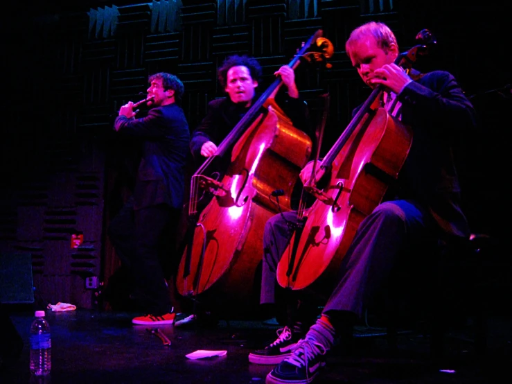 three musicians sit together on stage with their instruments