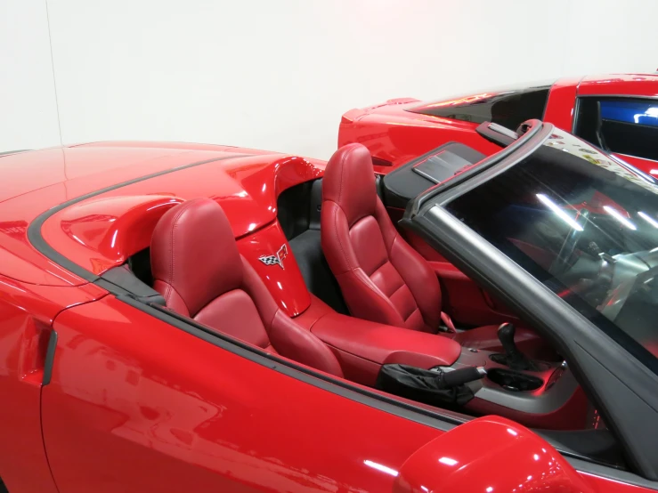 a red car inside of a showroom with other cars